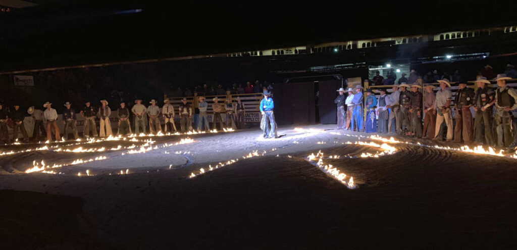 Photo of fire lighted "PBR" drawn in the dirt of the arena