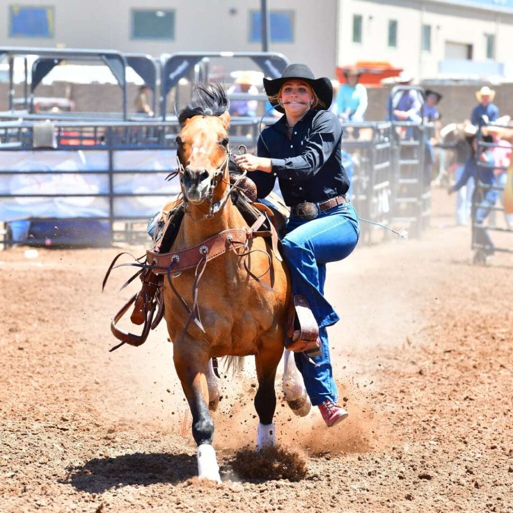 Female athlete jumping off horse to wrestle an animal. Photo credit UHSRA