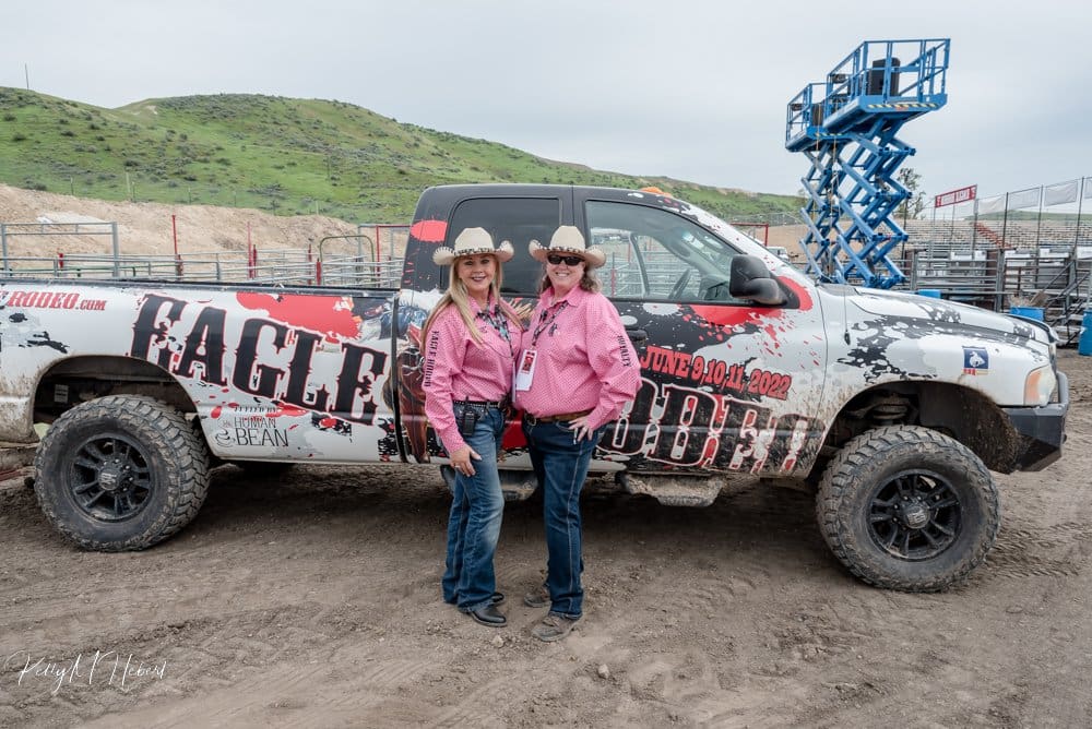 Two Eagle Rodeo Committee members wearing Tough Enough to Wear Pink shirts in front of Eagle Rodeo truck.