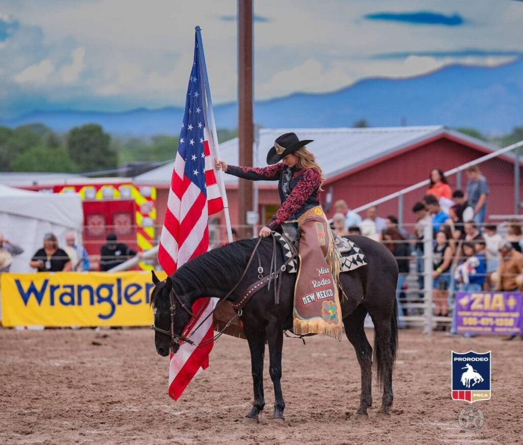 Miss Rodeo New Mexico on horseback holding flag