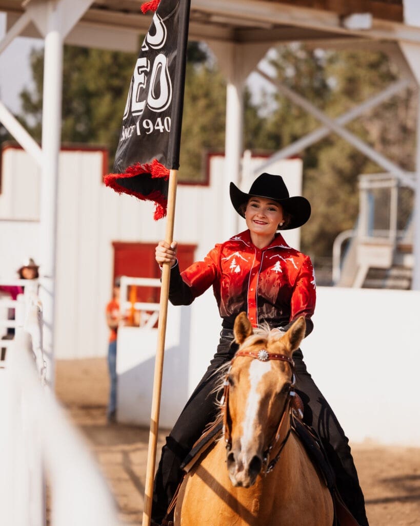 Rodeo girl on horseback with Rodeo flag. Photo courtesy Sisters Rodeo