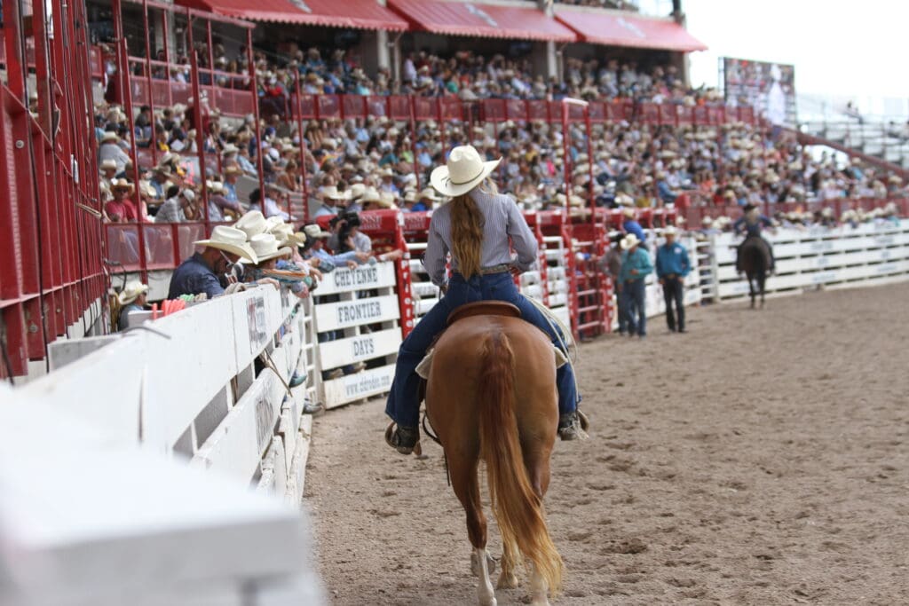 Cowgirl riding horse along arena fence