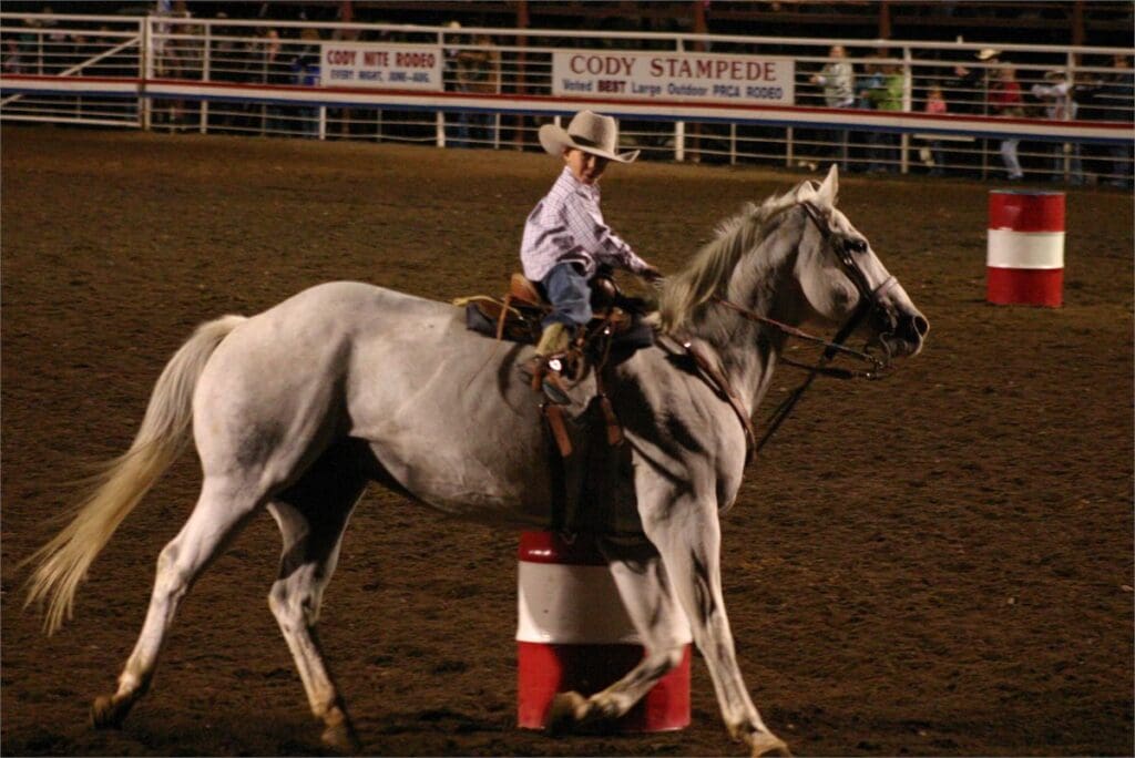 Young boy Cayden on white horse barrel racing at Cody Nites Rodeo