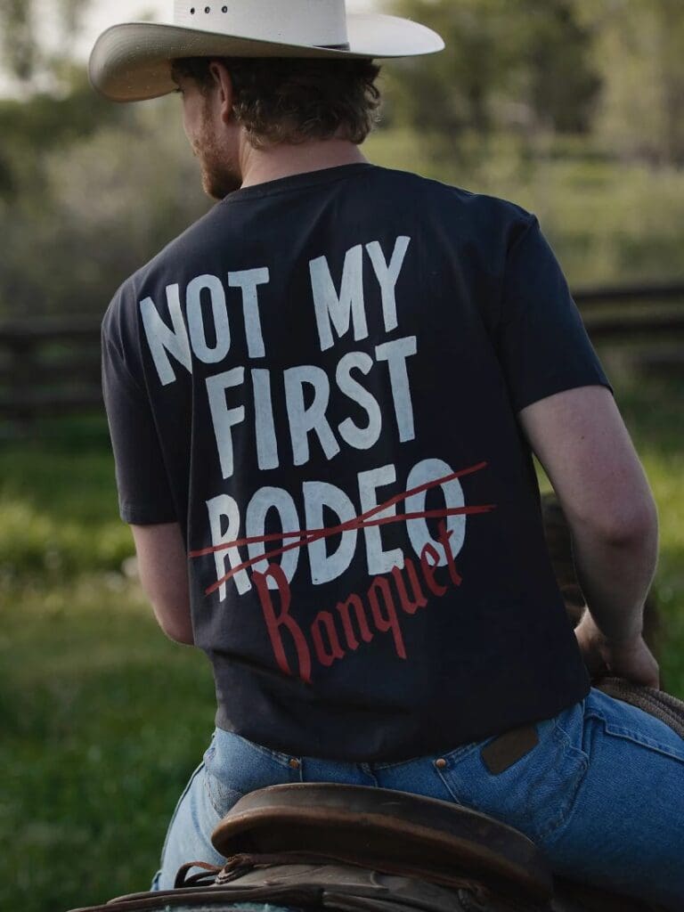 Man riding a horse wearing a Wrangler Coors Rodeo T-Shirt