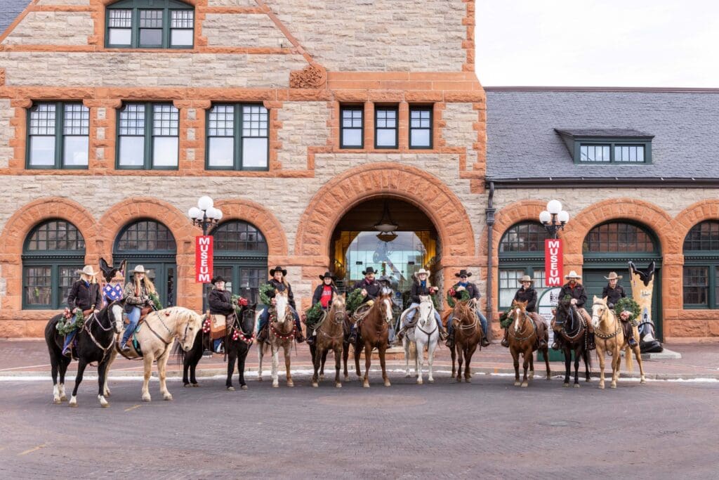 Horseback riders dressed in holiday spirit in front of the Cheyenne Museum