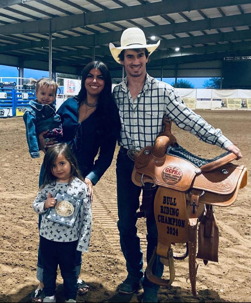 2024 bull riding Champion standing with family and the winners saddle