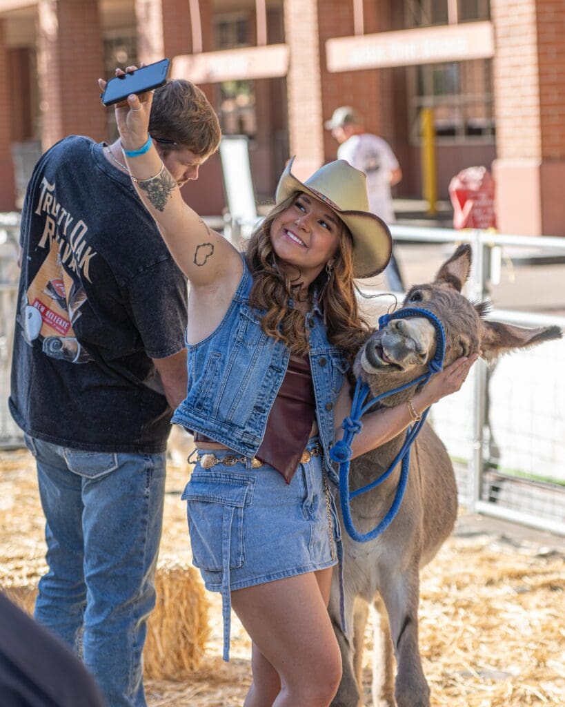 Hondo Street Fest fan posing with donkey at the petting zoo