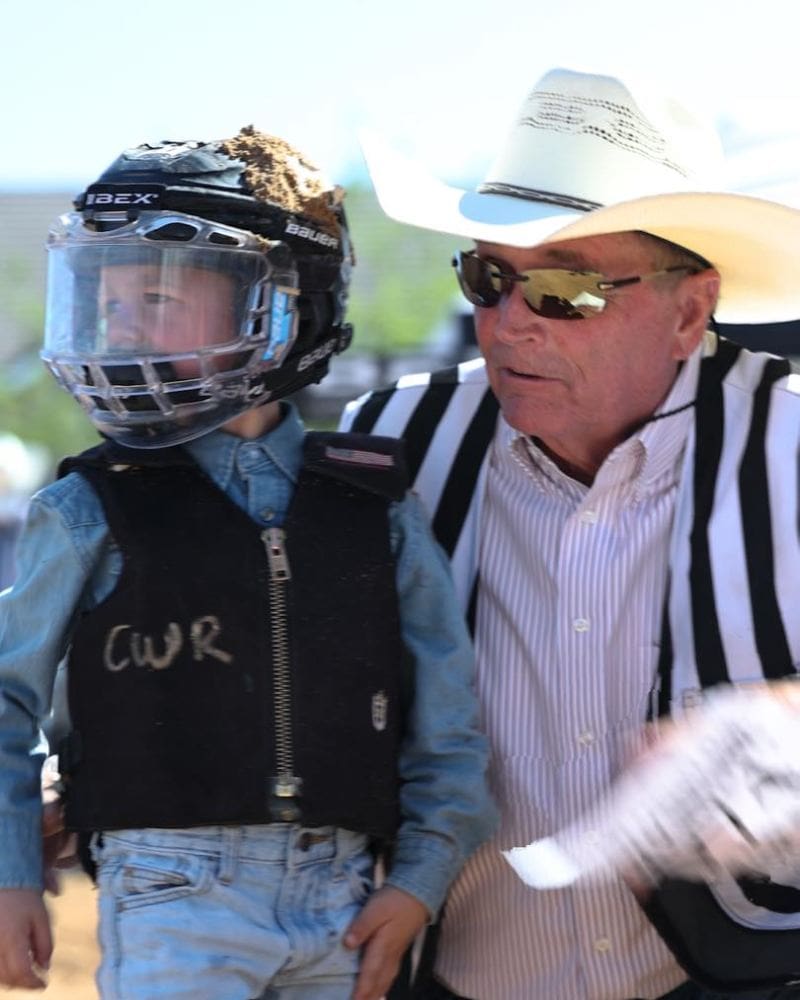Young rider geared up in a vest and head gear waiting to perform at Mutton Bustin'