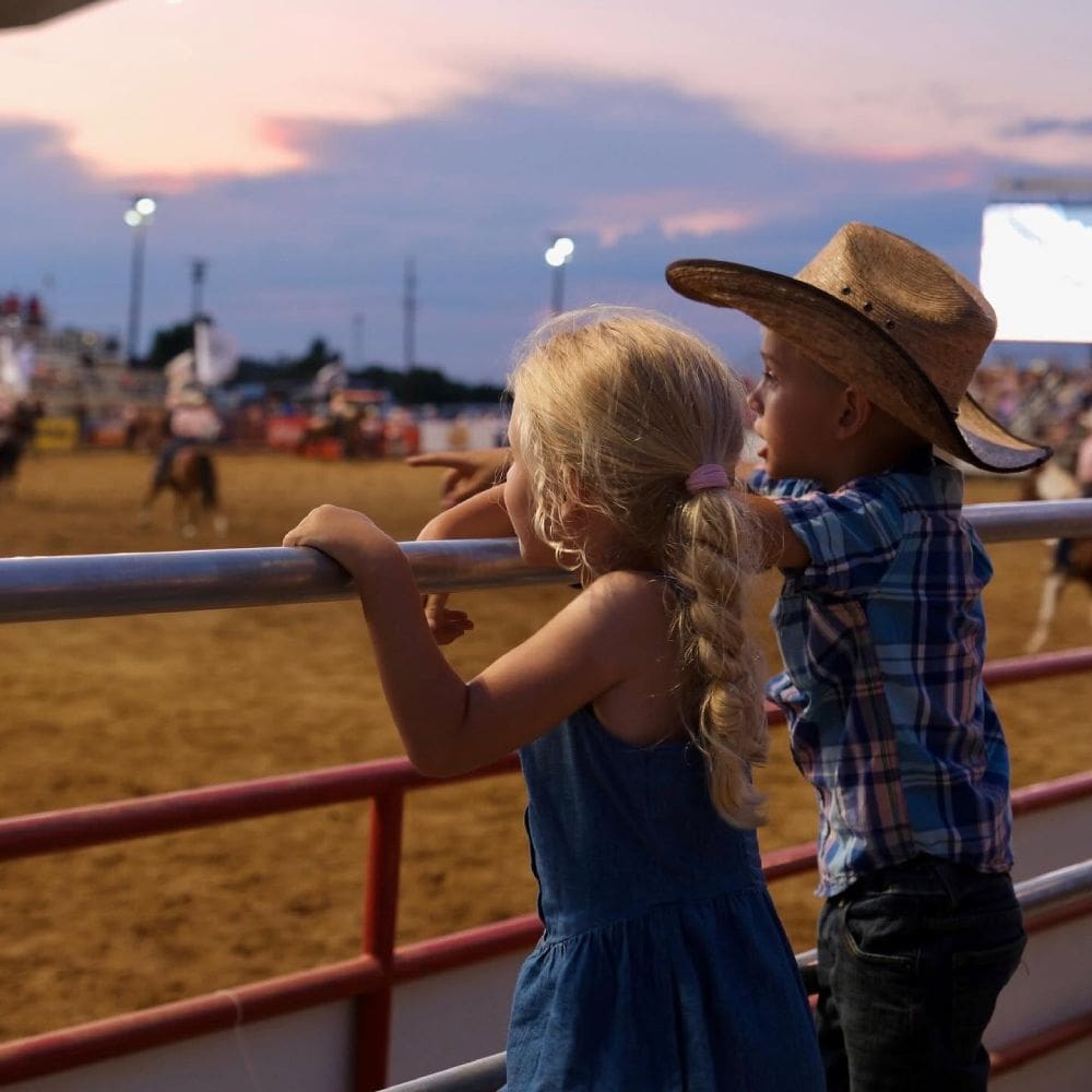 Kids watching rodeo excitement.