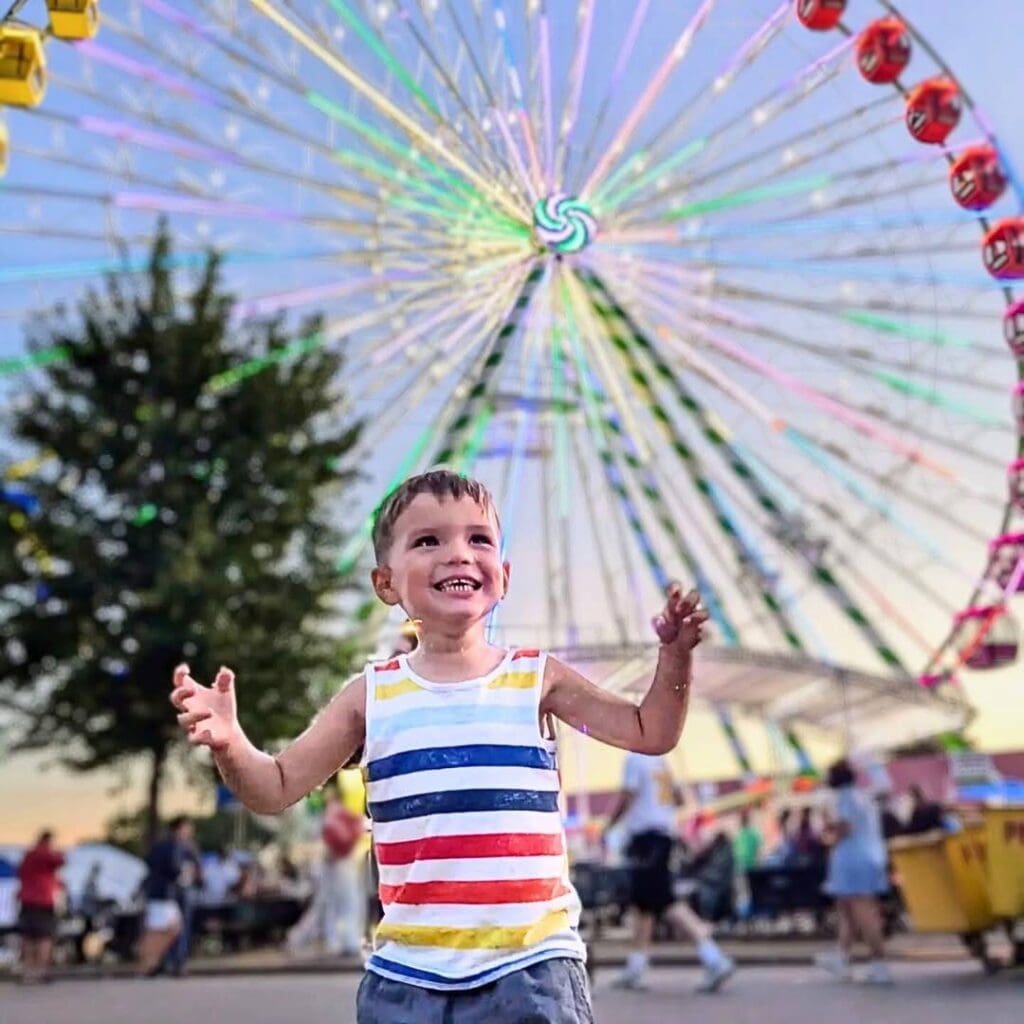 Excited young boy in front of a ferris wheel