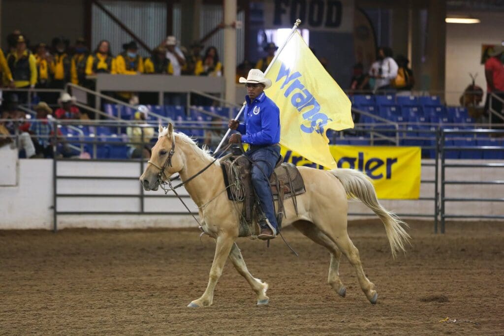 Cowboy carrying a Wrangler flag in the arena